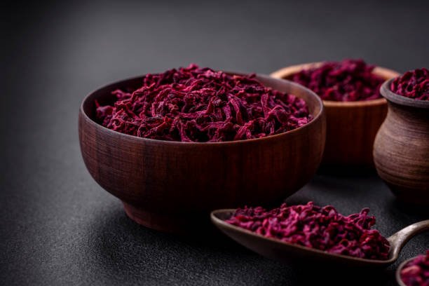 Dried beets in small slices in a wooden bowl on a black concrete background. Asian cuisine